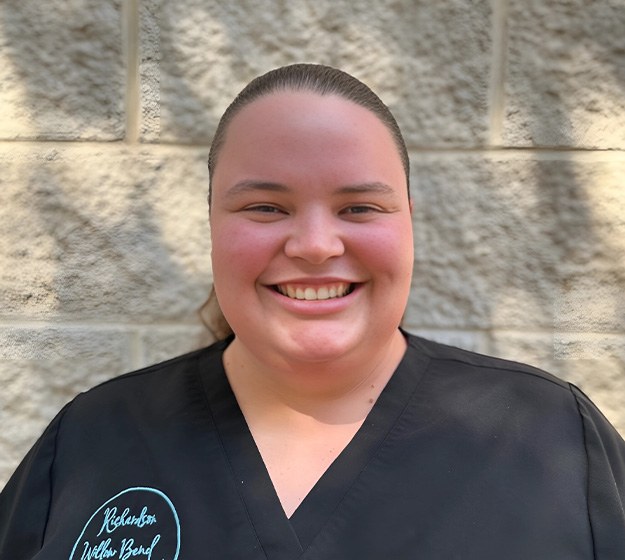 A female dental receptionist answers the phone while standing behind the front desk in Richardson