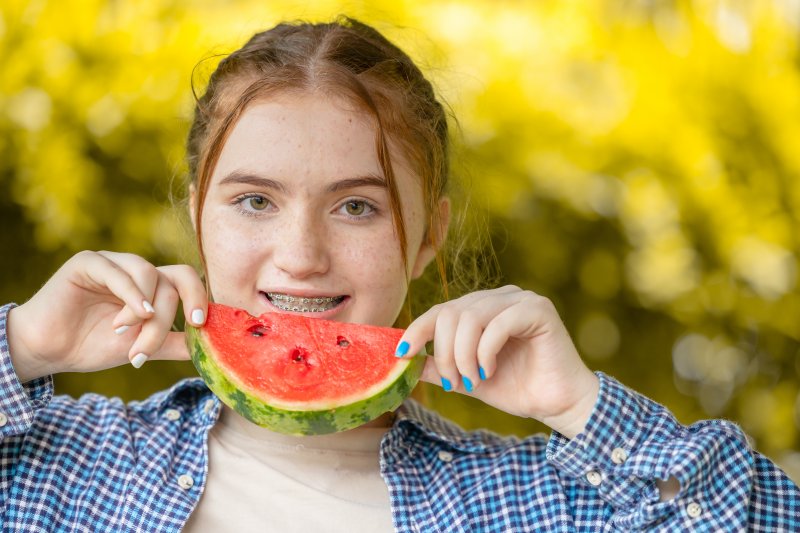 Patient smiling with braces eating watermelon