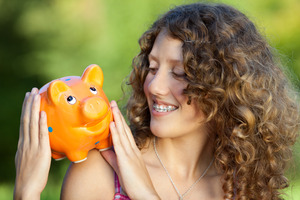 Someone with braces holding a piggy bank